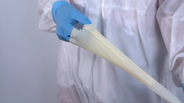 Nurse in PPE protective suit taking off latex gloves