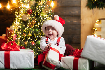 Happy Little baby in Santa hat celebrates Christmas. Smiling Infant in New Year red cap.