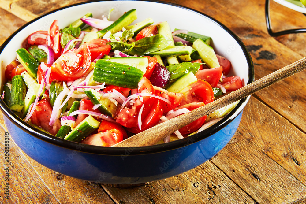 Canvas Prints Salad of cucumbers, tomatoes, onions and herbs in a blue-white bowl on a wooden background