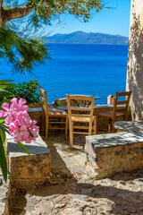 Traditional cafe exterior in the fortified medieval  castle of Monemvasia. Iron tables and wooden chairs with the view of the  aegean sea in the background.
