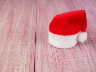 Obraz na płótnie Canvas small Santa Claus hat on a wooden background, symbol of Christmas, minimalism