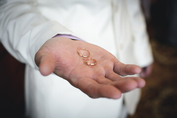 two gold wedding rings lie on the hand of the groom's man