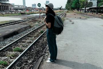 Asian woman backpacker waiting for a train at station.