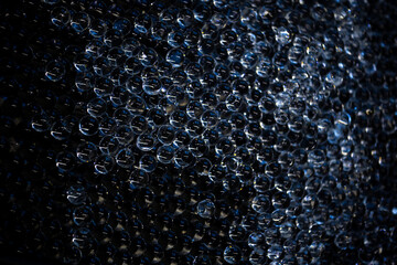 Background of small transparent hydrogel balls illuminated with blue light
