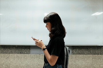 Sideview asian woman using smartphone over white board background.