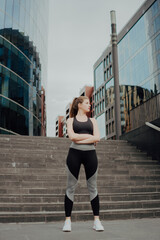 Young sports girl shared a plan, stands against the background of the building.