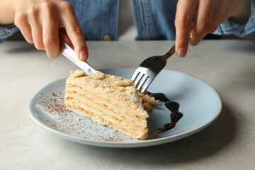 Woman eating delicious Napoleon cake, close up
