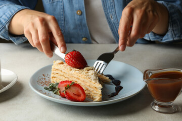 Woman eating delicious Napoleon cake, close up