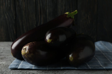 Napkin with fresh eggplants and knife on gray background