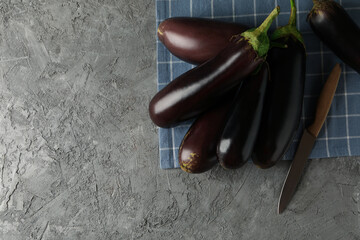 Napkin with fresh eggplants and knife on gray background