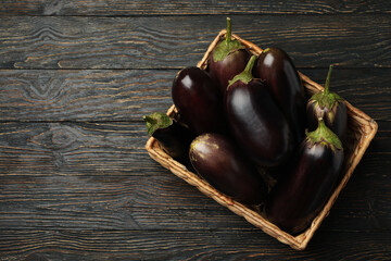 Basket with fresh eggplants on wooden background