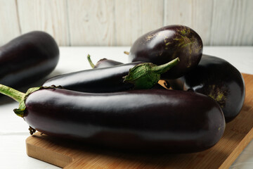 Board with fresh eggplants on wooden background