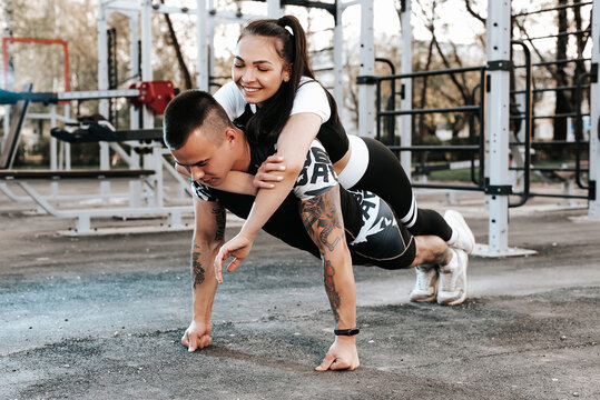 trong athletic man does push-UPS with his girlfriend on the outdoor