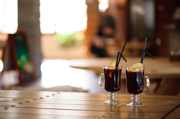 two glasses with hot tasty mulled wine on a wooden table in a cafe