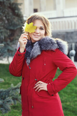  blond business woman in red fox fir dawn jacket with hood closeup photo on city park background