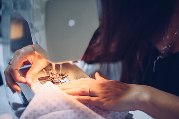Obraz premium A young long-haired woman sews with her machine