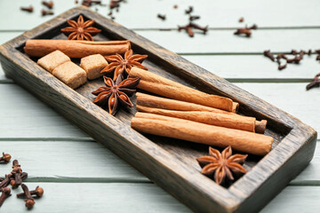 Plate with cinnamon, anise and sugar on wooden background