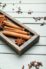 Plate with cinnamon and anise on wooden background