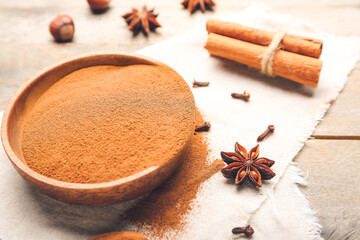 Bowl with cinnamon powder on wooden background