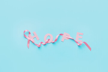Pink ribbon and word HOPE on color background. Breast cancer awareness concept