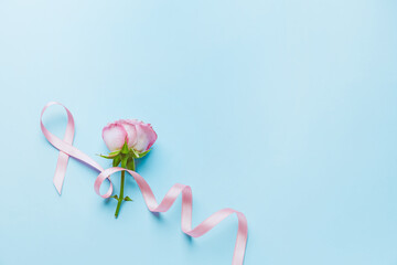 Pink ribbon and rose on color background. Breast cancer awareness concept