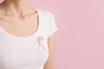 Woman with pink ribbon on color background. Breast cancer awareness concept