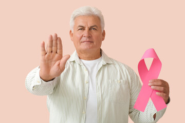Mature man with pink ribbon on color background. Breast cancer awareness concept