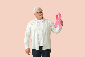 Mature man with pink ribbon on color background. Breast cancer awareness concept