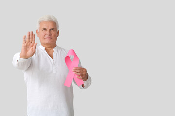 Mature man with pink ribbon on light background. Breast cancer awareness concept