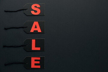 Word sale written on black cardboard paper labels or price tags with cord isolated on dark background. Black Friday, Shopping, sale and marketing concept. Top view, flat lay, copy space.