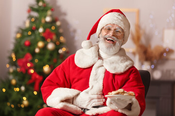 Santa Claus with tasty gingerbread cookies at home