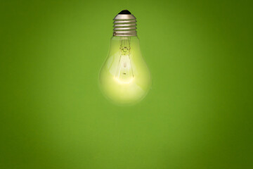 Light bulb glowing on green background