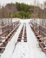 Obraz premium Metal bridge with snow across the river in early winter on the background of the forest