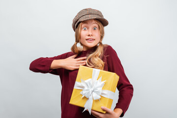 Charming blonde girl with gift posing with surprised face expression. Studio shot white background, isolated