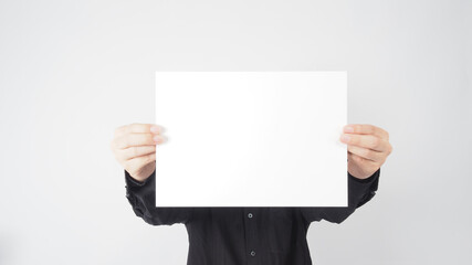 Empty space for text.Male asian wear black shirt and hand is holding the A4 paper on white background.