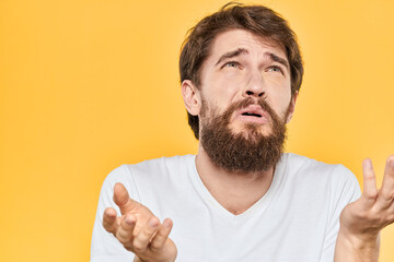 Bearded man emotions gestures with hands facial expression white t-shirt yellow background