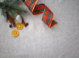 Top view of linen background with dried orange slices and cinnamon sticks and red ribbon for gifts