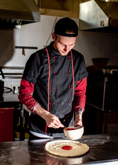 Pizza cooking concept, chef puts ketchup on pizza