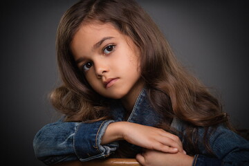 portrait of adorable little girl in denim jacket on gray background