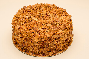 Beatiful nut biscuit cake finished with crushed sugar-coated candied caramelized almonds on a table