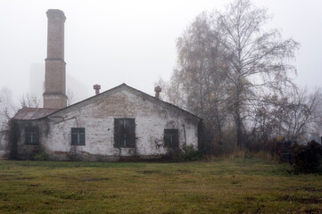 Fototapeta na wymiar Building of an old boiler house with a pipe in foggy autumn weather