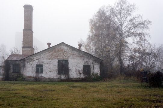 Building of an old boiler house with a pipe in foggy autumn weather