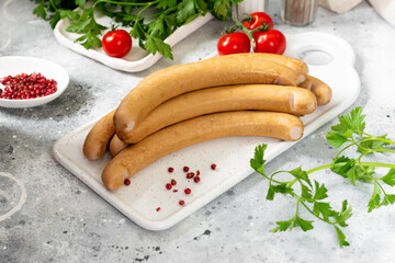 Viennese sausages. Sausages on a white serving Board on a light gray table. German sausages	
