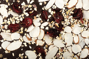 Macro shot of almond, pistachio and cranberry slices on dark chocolate.