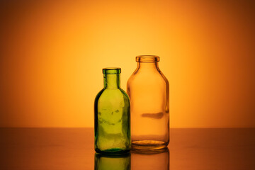 Old pharmacy glassware. Two old pharmacy glass bottles on an orange background in the background light.