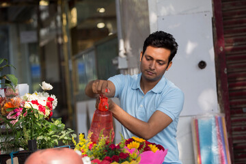 One young male florist in uniform, at the flower shop portrait.