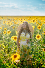 Fototapeta na wymiar Beautiful caucasian pregnant woman walking in the summer at sunset in a field of blooming sunflower