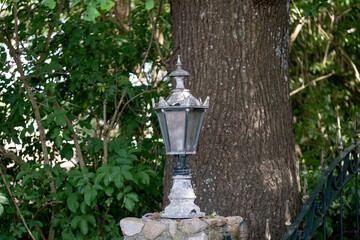 A lantern or lamp made of metal on a brick post. Old retro style