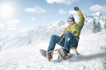 Happy man riding on a sled in winter