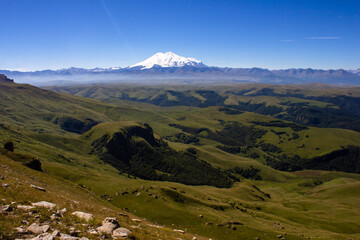 An excellent view from the plateau to the extinct volcano and the snowy peak of Mount Elbrus. Below is a green gorge